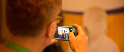 A man is looking at the view screen of a digital camera. On the screen is a black man standing