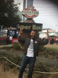 Kriston Pumphrey stands in front of a large sign that says Houston at the top and Super Bowl below.
